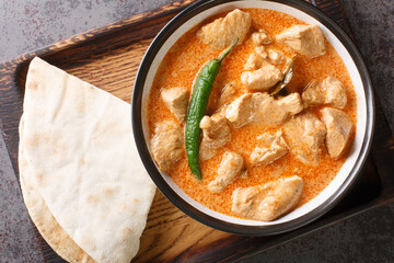 Chicken curry with coconut milk and sri lanka spices in a bowl on a wooden tray. Horizontal top view from above