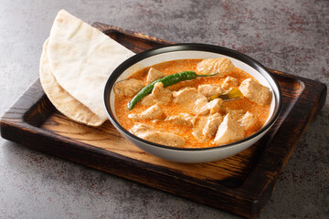 Kukul mas is a traditional Sri Lankan chicken curry made with a onions, ginger, garlic, turmeric, garam masala, chili powder, coconut milk, tomato in the bowl on the table. Horizontal