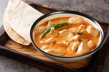 Spicy Kukul Mas chicken breast curry with coconut milk and spices close-up in a bowl on a wooden tray. Horizontal
