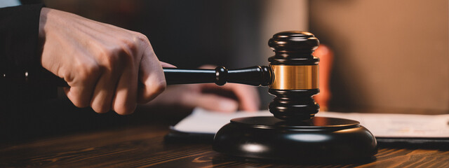 Banner background of A picture of a hand hitting a hammer. The gavel blow of a judge or decision-maker to authority about business, justice, or the law for a court proceeding.