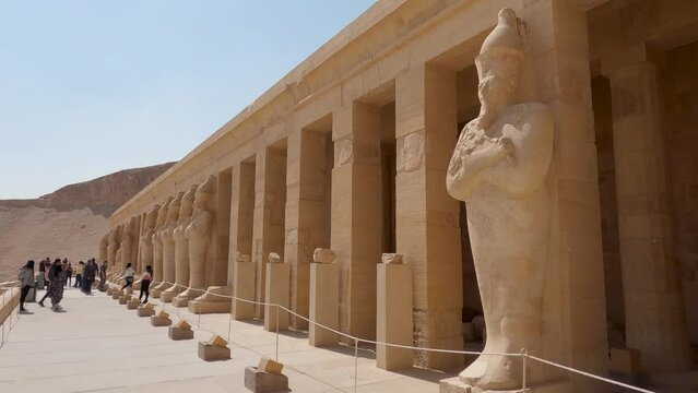 Looking Across Row Of Colonnade At The Mortuary Temple Of Hatshepsut On Sunny Day With Tourists