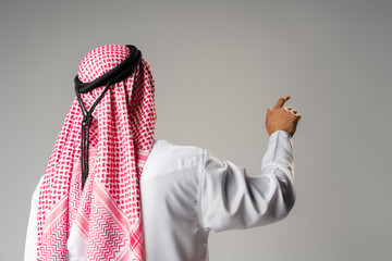Back view of young Arab man standing on gray background