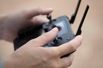 Close up of young woman's elegant hands on drone remote controller against a neutral and out of focus background. © Paul