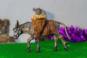 Tuinposter Close up of a Christmas figure of a donkey carrying straw © JuanM