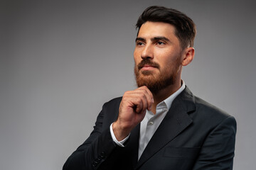 Studuo shot of thinking businessman standing over gray background