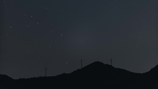 Perseids meteor shower over wind turbines in the skyline.