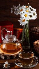 Obraz na płótnie Canvas A teapot and a mug of tea on a wooden table and a bouquet of daisies