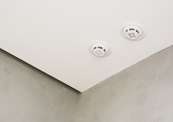 A close-up of a ceiling with a smoke alarm system, smoke detector indoor.