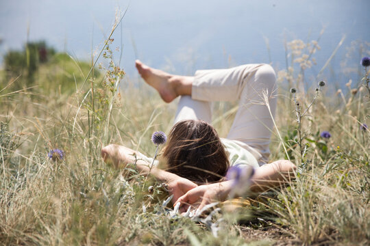 middle aged woman with a backpack  rests on the grass outdoor. copy space. Slow life. Enjoying the little things. spends time in nature in summer. Lykke concept