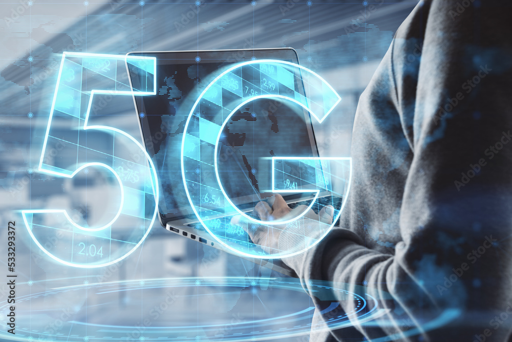 Poster hacker hands using laptop with abstract glowing 5g hologram on blurry office interior background. mo