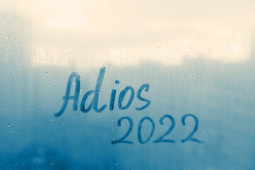 lettering Adios in Spanish is goodbye in english and numbers 2022 paint with finger of water on...
