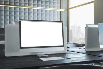 Modern blank white computer monitor with space for your logo or text on dark wooden work place table with partition behind in coworking office with city view. 3D rendering, mock up