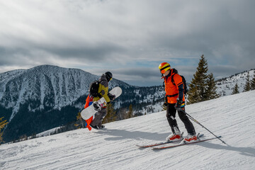man snowboarder going up skier sliding by slope