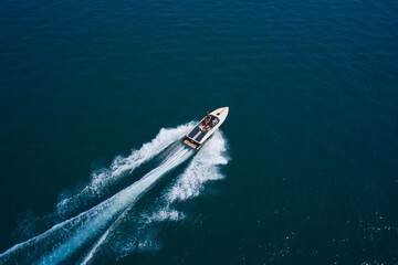 Luxurious boat fast movement on dark water. Luxurious  motor boat rushes through the waves of the blue Sea. Boat fast moving aerial view.