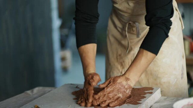 A male potter kneads brown clay on a special board. Professional everyday life