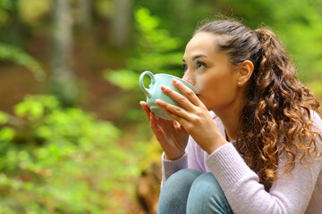 Woman drinking coffee in a forest
