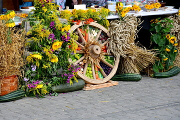 A close up on a basket and a cross made out of hay, wheat, fruits, vegetables, and other harvested crops seen during a folk harvest festival organized in Poland during summer