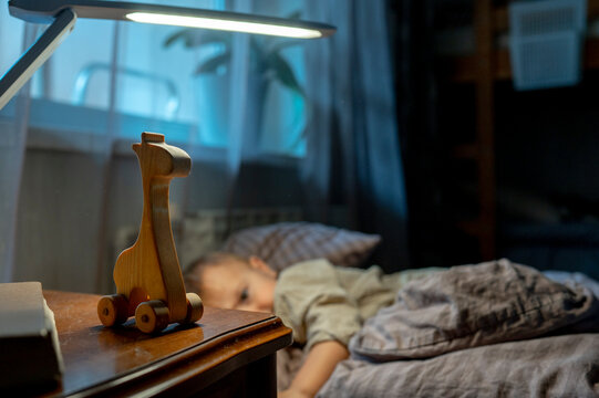 Wooden toy on table with boy in background at home