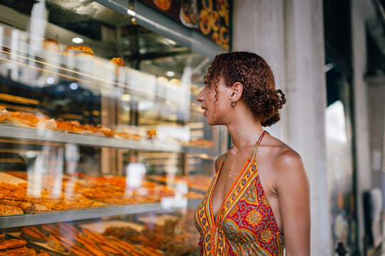 Young woman looking through delicatessen store window