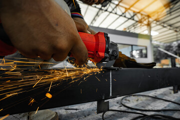 Picture of an Asian welder welding a steel structure in a factory building.
