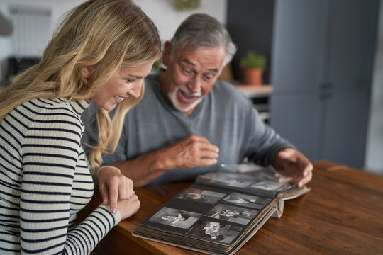 Caucasian woman looking at old pictures in album with senior dad