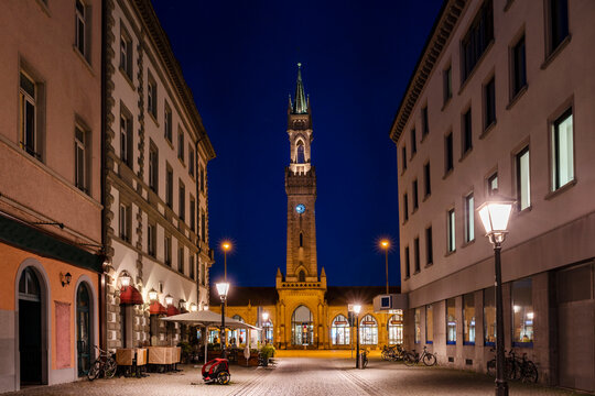 Germany, Baden-Wurttemberg, Konstanz, Illuminated street at night with facade of Konstanz Station in background