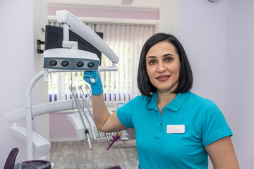 young female dentist in a private clinic with modern dental equipment standing and smiling.