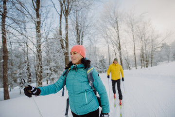 Fototapeta na wymiar Senior couple skiing togetherin the middle of forest