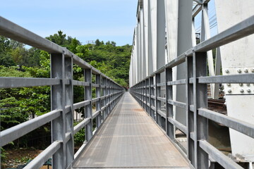 A metal bridge for trains with a perspective passage for pedestrians.