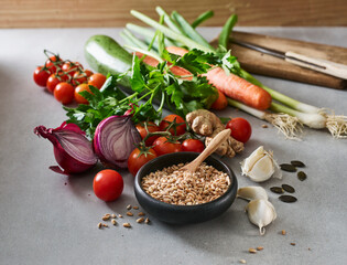 Bowl of grains, garlic, ginger, pumpkin seeds, parsley and various raw vegetables
