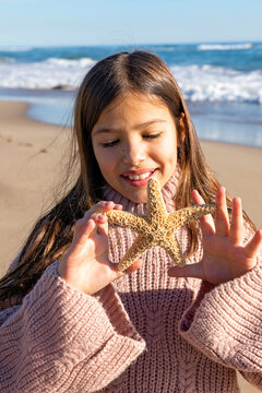 Girl playing with starfish at beach on sunny day