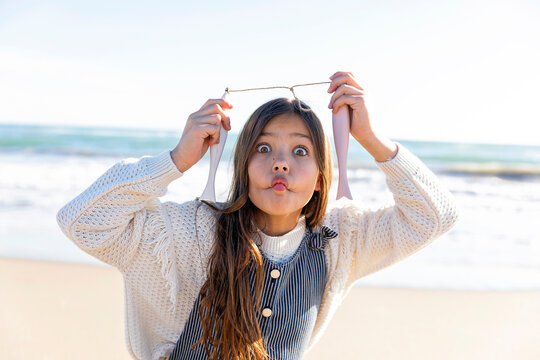 Girl making face with artificial fish at beach