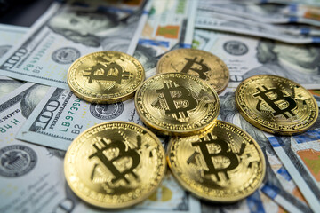 Golden bitcoin symbolic coin isolated on hundred dollar bills.