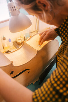 Instrument maker with tool carving on double bass in workshop