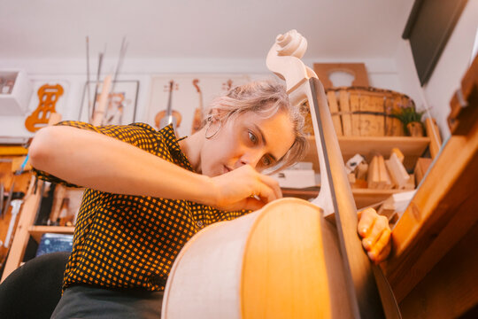 Luthier working on double bass in musical instrument workshop