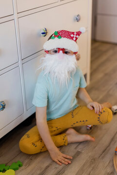 Boy wearing Santa beard and hat at home