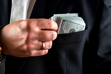 businessman or bank employee counting one hundred dollar bills in front of him with his hands