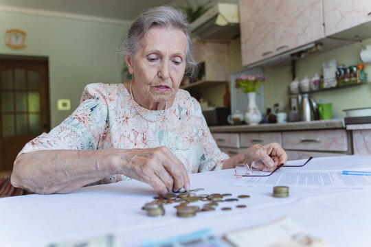 Senior woman counting savings and doing paperwork at home