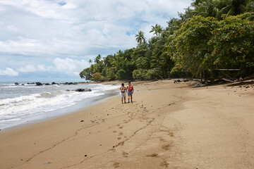 Couple walking on the tropical beach in Corcovado national park, Costa Rica.
