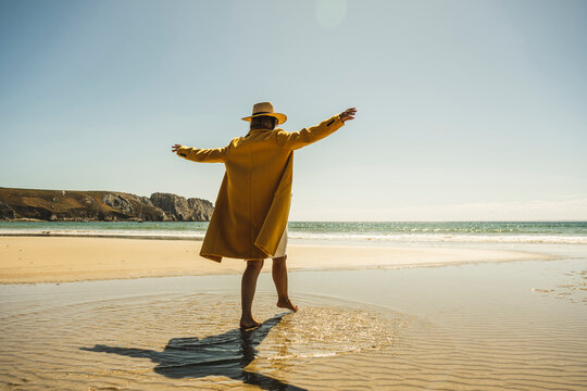 Mature Woman With Arms Outstretched Enjoying Vacations At Beach