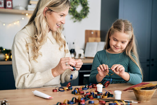 Caucasian girl and mother preparing DIY paper chain for Christmas tree and talking - Powered by Adobe