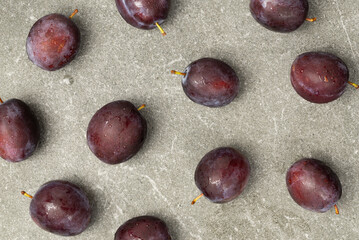 Blue plums lie on granite over the entire surface