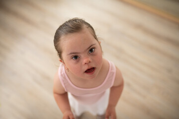 High angle view of little girl with down syndrome at ballet class in dance studio. Concept of integration and education of disabled children.