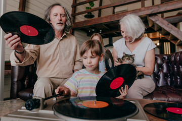 Granddaughter changing record on turntable with grandparents at home