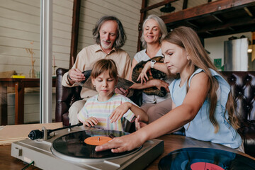 Granddaughters playing music on vinyl record player with grandparents at home