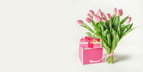 Lovely tulips bunch with pink gift box standing on white background. Banner for holiday greeting