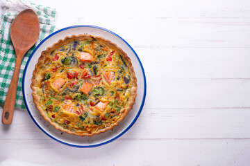 Salmon and vegetable quiche. Traditional French recipe with fish and fresh vegetables with handmade dough and egg.