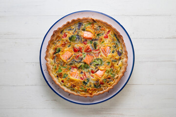 Salmon and vegetable quiche. Traditional French recipe with fish and fresh vegetables with handmade dough and egg.