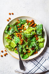 Vegan caesar salad with fried spicy chickpeas in a gray bowl. - obrazy, fototapety, plakaty