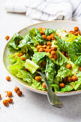 Vegan caesar salad with fried spicy chickpeas in a gray bowl.